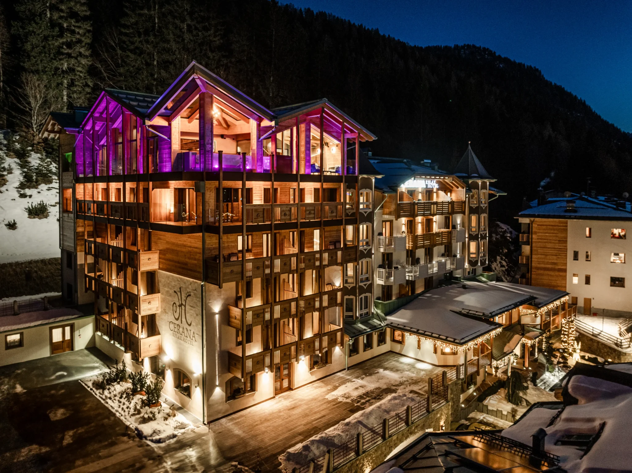 Hotel di montagna illuminato di notte con neve attorno.