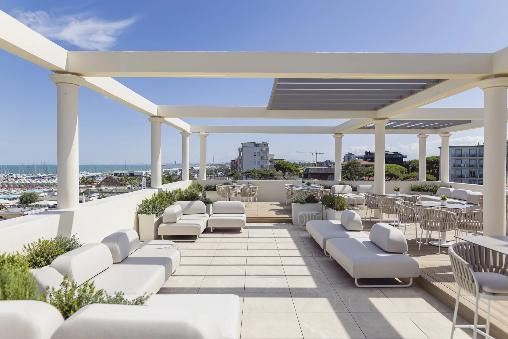 Terrazza moderna con salotti bianchi e vista sul mare.