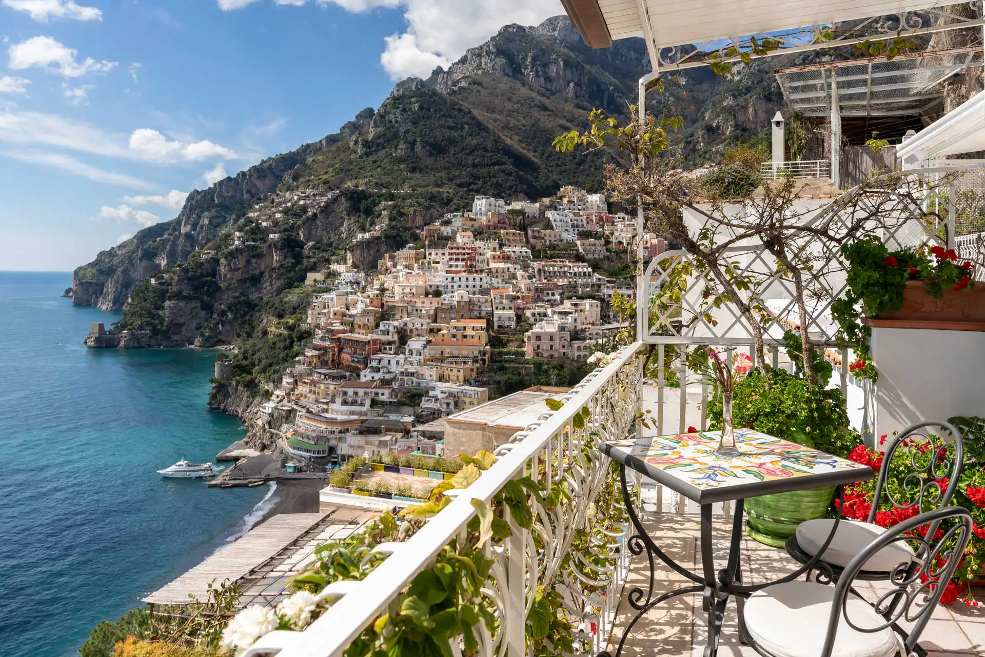 Vista panoramica di Positano con terrazza affacciata sul mare e montagne.