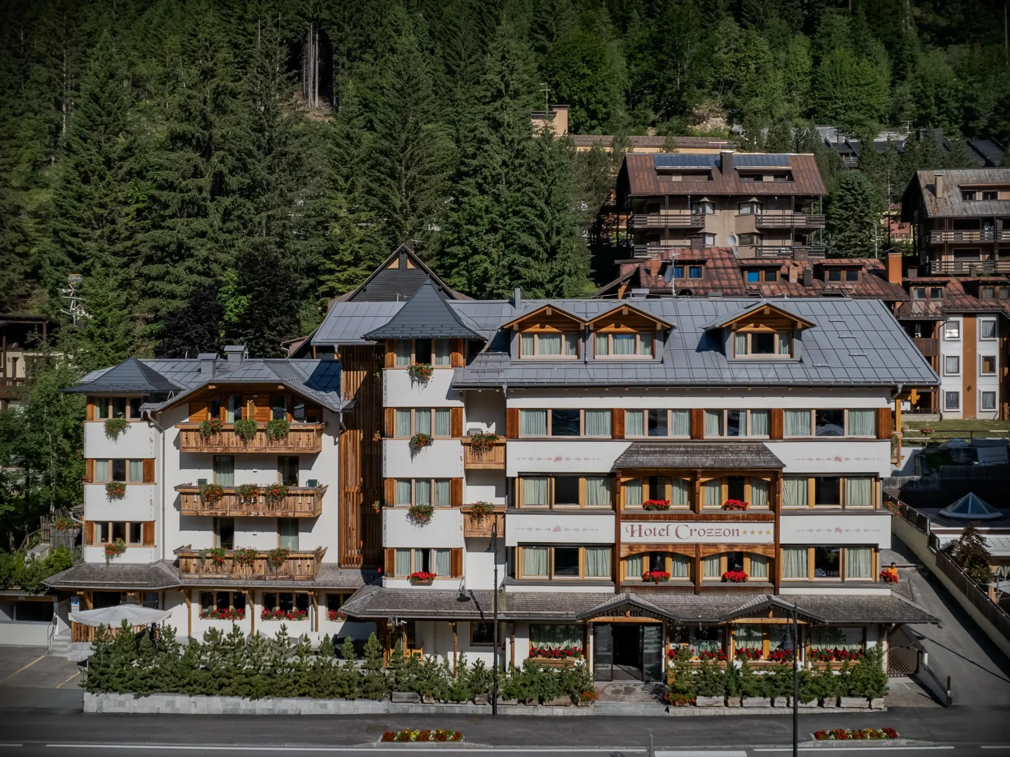 Hotel montano circondato da foresta e chalet alpini.