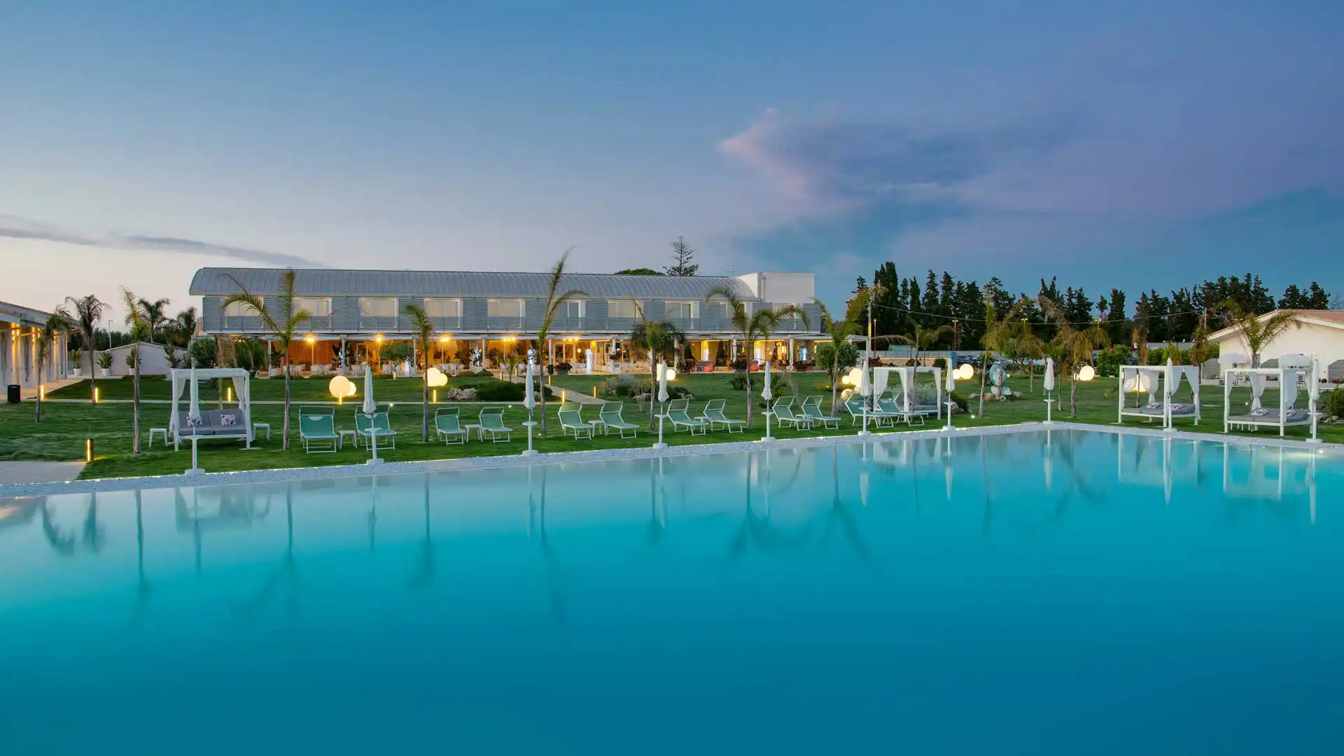 Piscina all'aperto con vista su un elegante resort al tramonto.